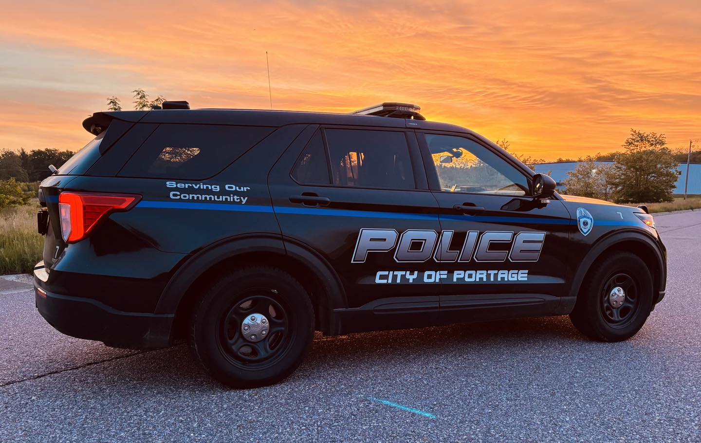 Image of a Portage Police Department squad car parked on a road with a sunset in the background.